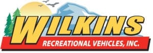 Logo for WKINGS Recreational Vehicles, Inc.: bold yellow wordmark over a mountain backdrop with a sun, trees, and a red ribbon banner.